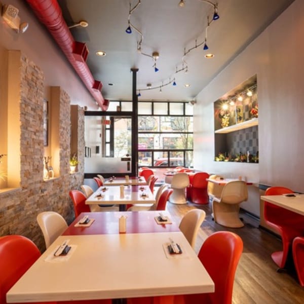 Interior of Seiko Japanese Restaurant with red and white tables, red chairs, and stone wall accents.