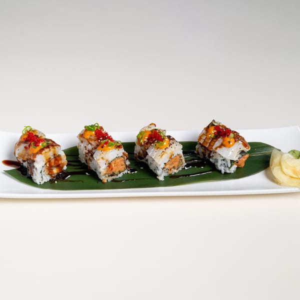Four pieces of Seiko Japanese Restaurant sushi rolls with sauce and roe, on a banana leaf.