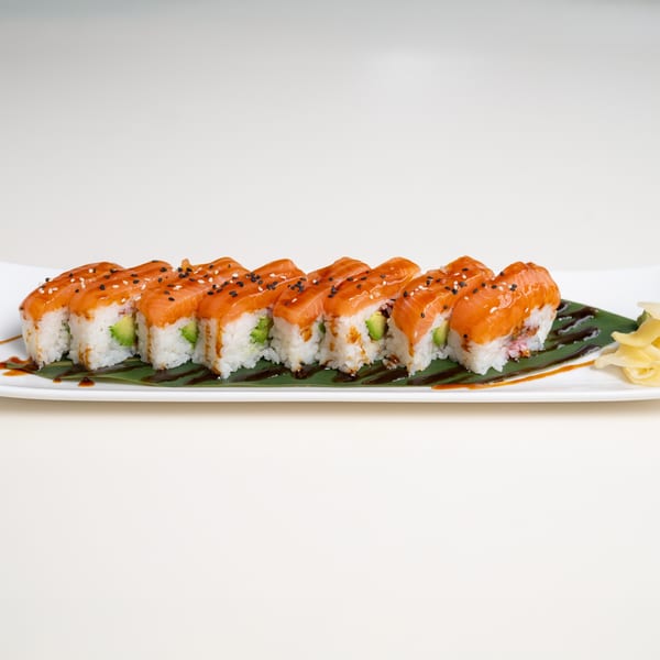 Seiko Japanese Restaurant's salmon and avocado sushi rolls with sauce and sesame seeds on a white plate.