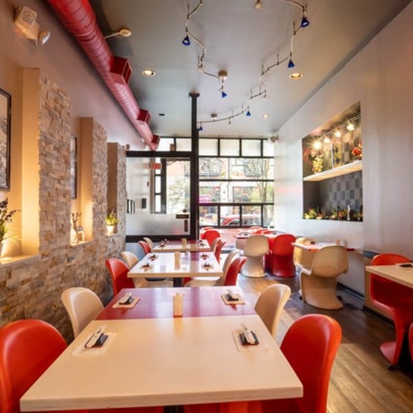 Seiko Japanese Restaurant interior with red and white tables, red chairs, and a stone accent wall.