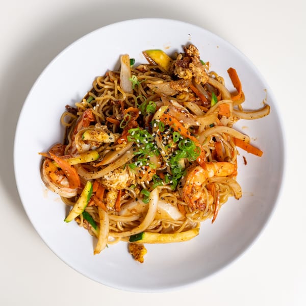 Seiko Japanese Restaurant's shrimp yakisoba with noodles, vegetables, and sesame seeds in a white bowl.