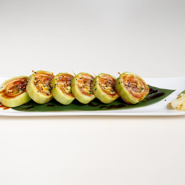Six pieces of Seiko Japanese Restaurant's sushi rolls, drizzled with sauce and sesame seeds, on a white plate.