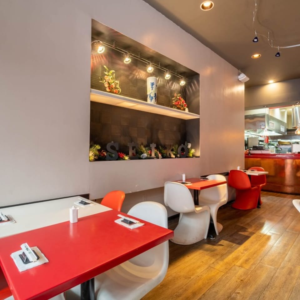 Seiko Japanese Restaurant dining area with red and white tables, modern chairs, and a decorative wall niche.