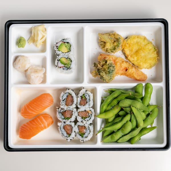 A bento box from Seiko Japanese Restaurant with sushi, tempura, edamame, and dumplings.