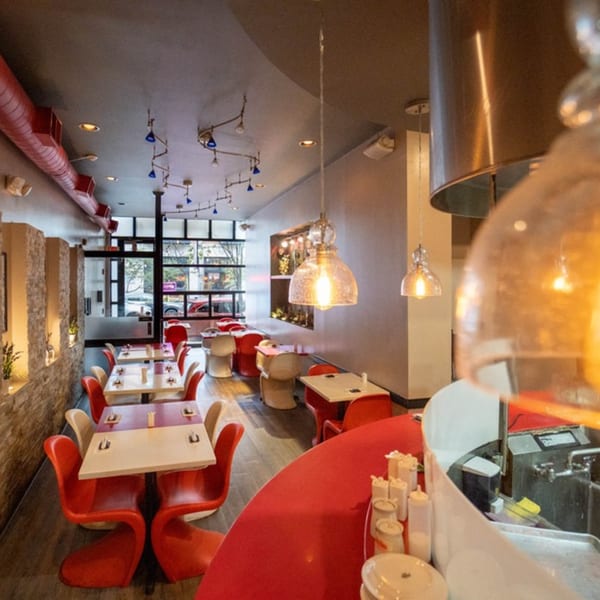 Seiko Japanese Restaurant interior with red chairs, white tables, and a red counter, bathed in warm lighting.