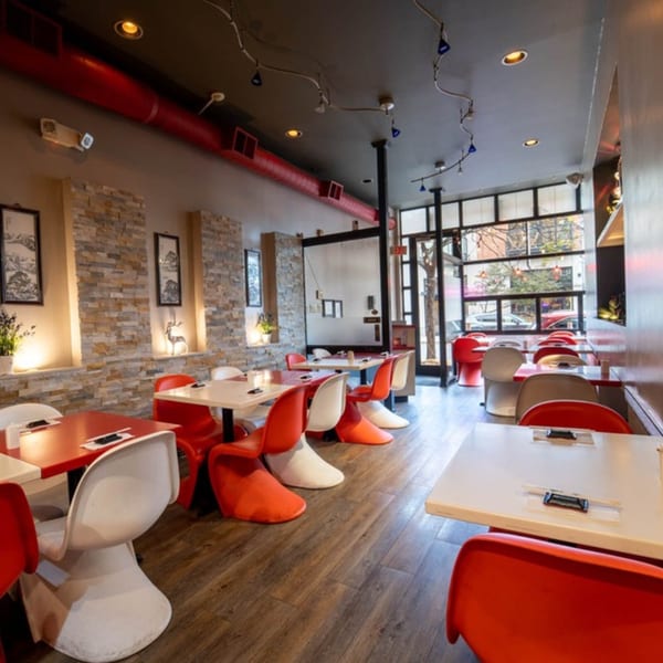 Seiko Japanese Restaurant interior with red and white chairs, light wood tables, and stone accent walls.
