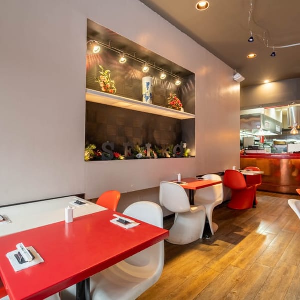 Interior of Seiko Japanese Restaurant with red and white tables, modern chairs, and a decorative wall niche.